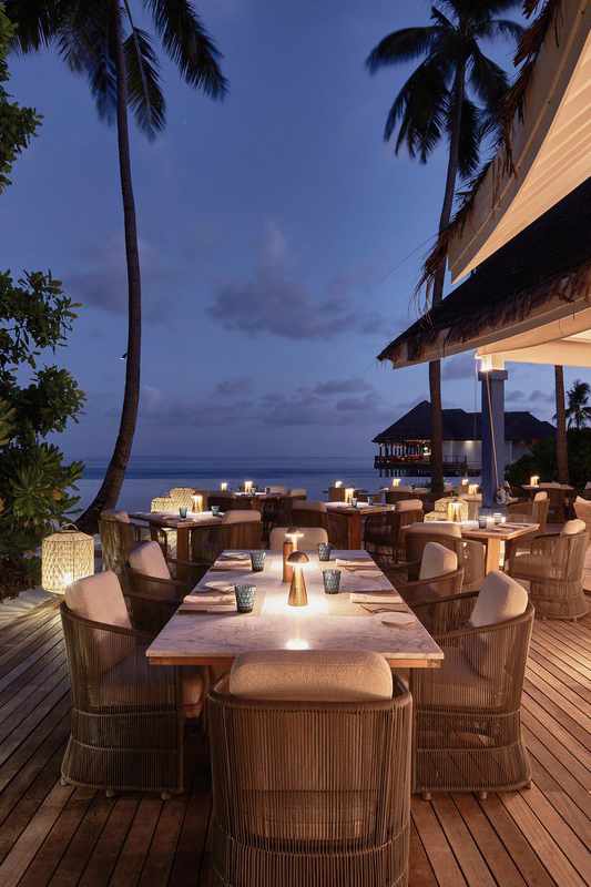 bltca8e19d733b9baa2-malediven-baa-atoll-kanifushi-finolhu-baa-atoll-maldives-tisch-am-abend-DER_ATC_MLE13132B_S23_21-f-indischer-ozean.jpg Terrassenansicht einer Hotelanlage am Abend