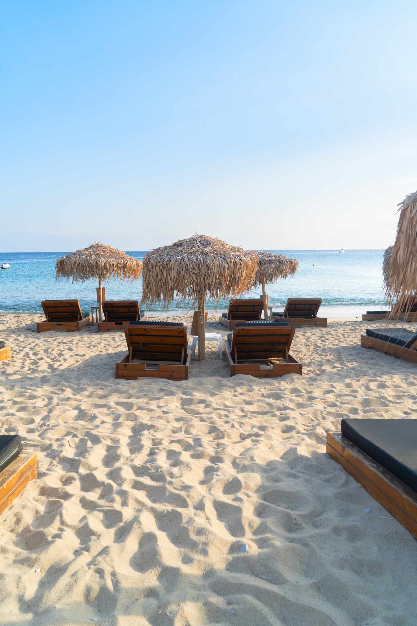 GettyImages-2217481941.jpg Holzliegen und Sonnenschirme am weißen Sandstrand