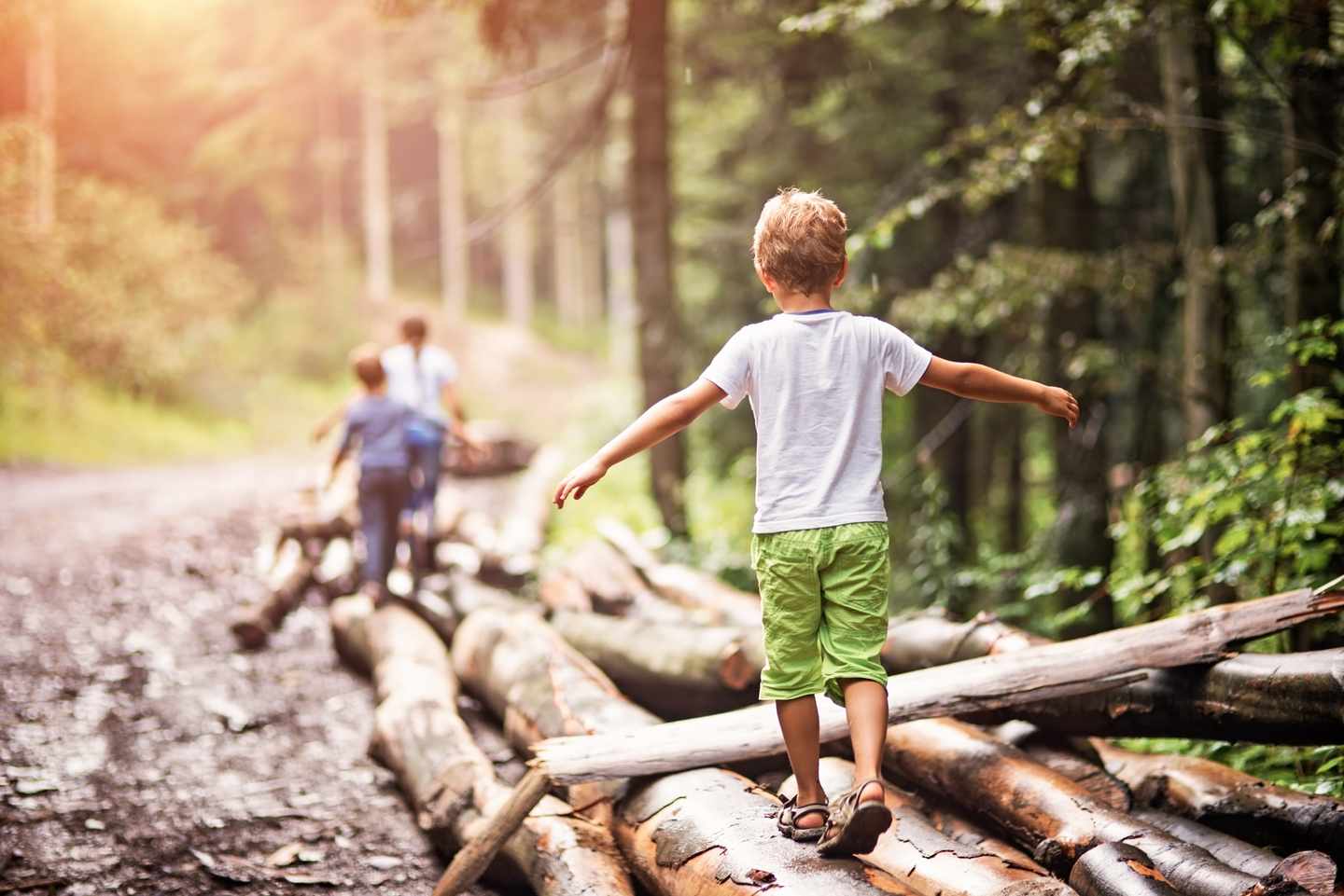 familienurlaub-ein-junge-balanciert-auf-einem-baumstamm-im-wald-g-624492258.jpg