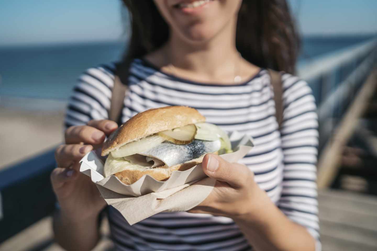 deutschland-schleswig-holstein-travemuende-frau-mit-fischbroetchen-g-1176970812.jpg