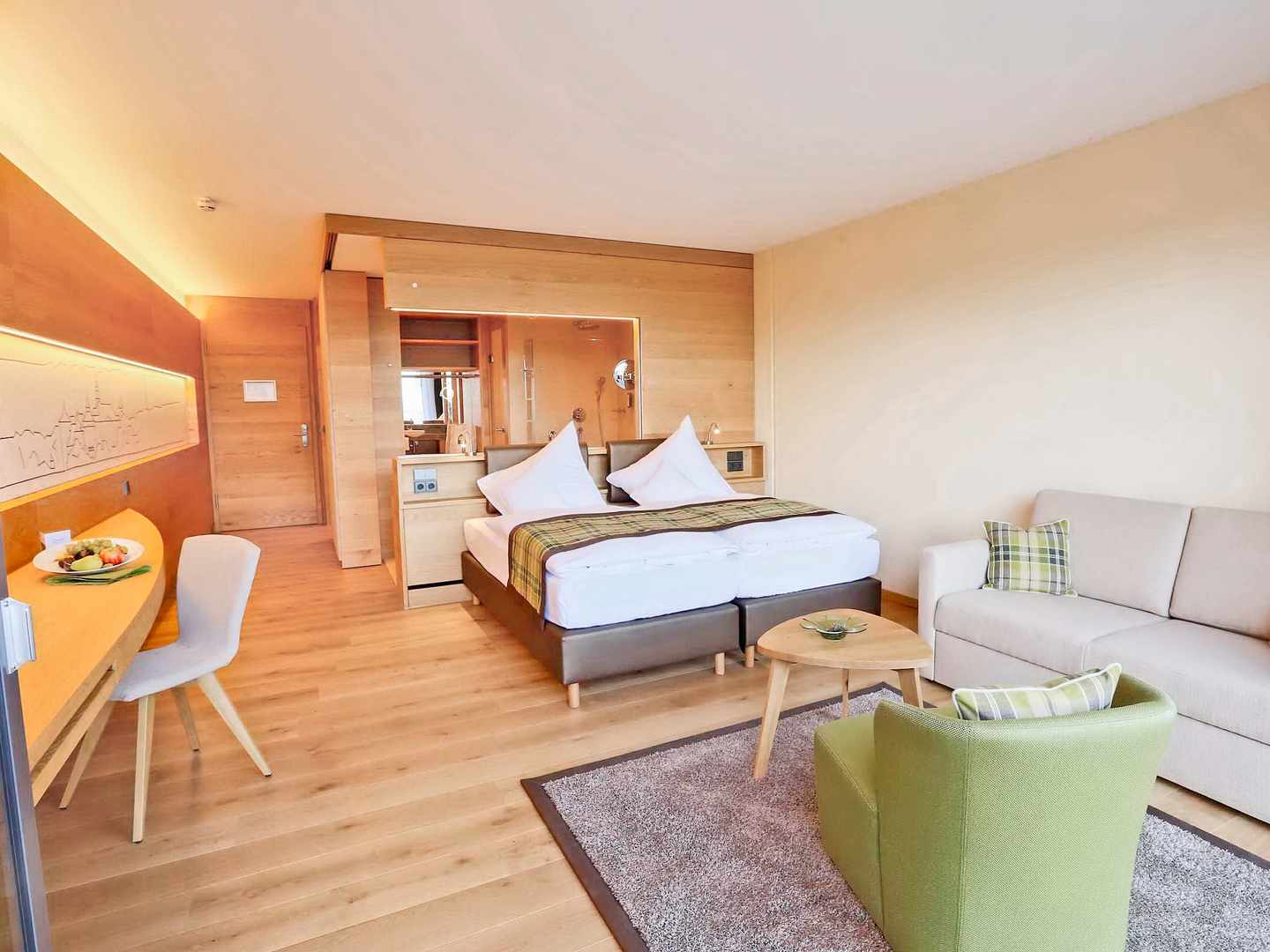 blt8e13e899359c2a0a-deutschland-baden-wuerttemberg-langenburg-mawell-resort-zimmer-wohnbereich-holzdesign-wellnesshotel-DER1077215.jpg Zimmer im Mawell Resort Langenburg mit Doppelbett, Sitzecke und hellem Holzdesign