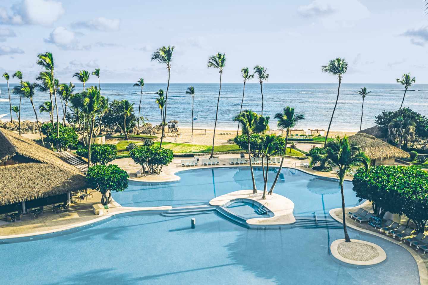 Die große Poollandschaft des Iberostar Selection Bavaro Suites mit Palmen und Strand im Hintergrund