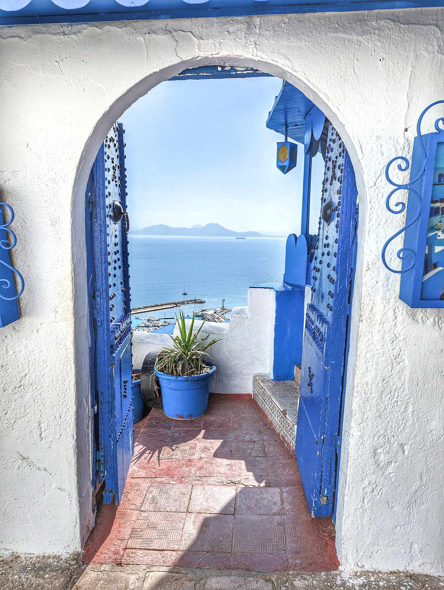 Blau-weißes Tor in Sidi Bou Said mit Blick auf den Hafen und das Mittelmeer an der tunesischen Küste