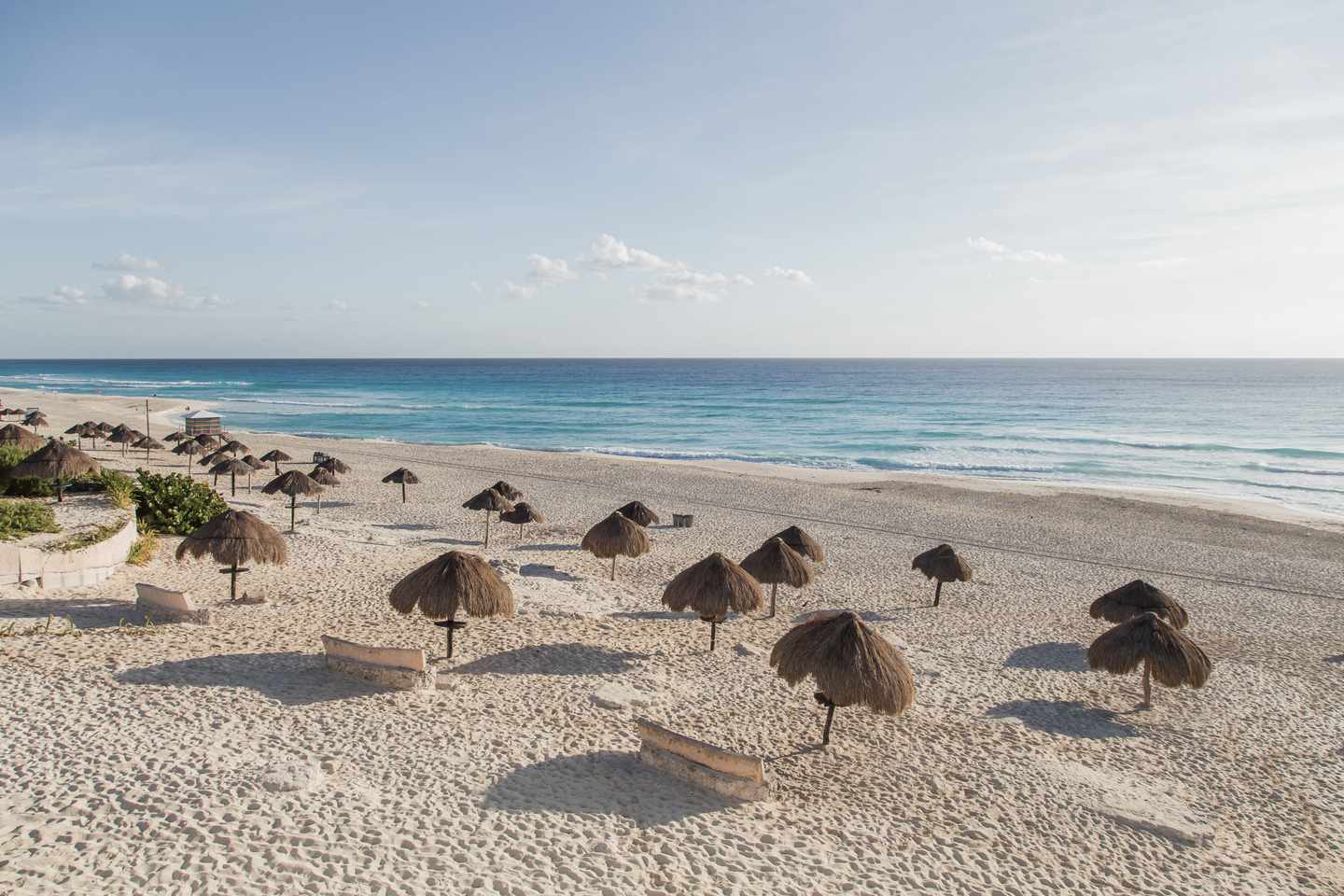 blt735d56211bfdb92d-mexiko-yucatan-cancun-playa-delfines-g-915151152.jpg Blick auf karibischen Sandstrand mit Sonnenschirmen aus Palmblättern
