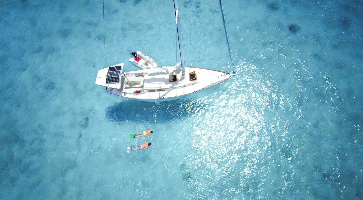 karibik-luxus-segelboot-solarenergie-schnorchelndes-paar-tuerkisblaues-meer-g-468205588