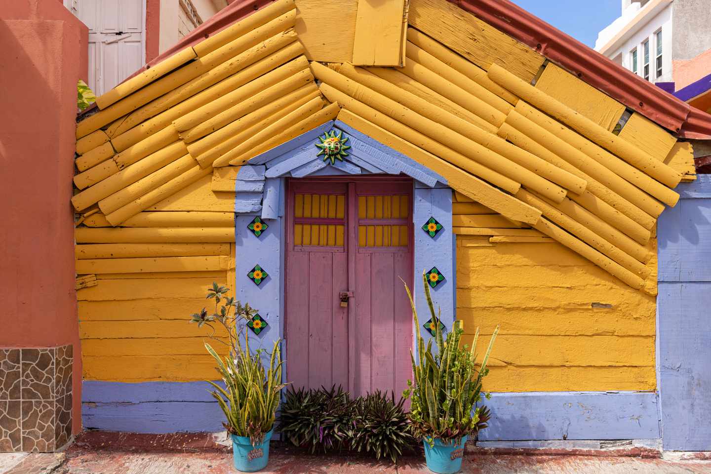 GettyImages-1355409843.jpg strahlend gelbe Hausfassade mit rosafarbener Tür auf der Insel Isla Mujeres