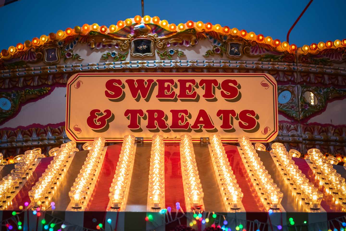Beleuchteter Süßigkeitenstand mit „Sweets & Treats“-Schild auf einem Weihnachtsmarkt in London