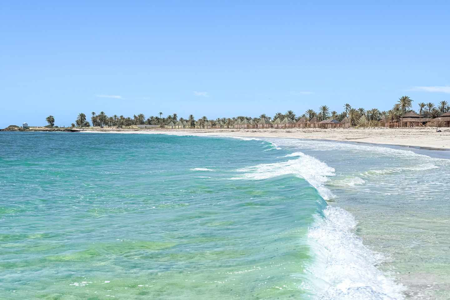 bltc105160efc1abf1e-tunesien-djerba-strand-g-1320799329.jpg Türkisblaues Meer und heller Sandstrand auf Djerba mit sanften Wellen und Palmen im Hintergrund