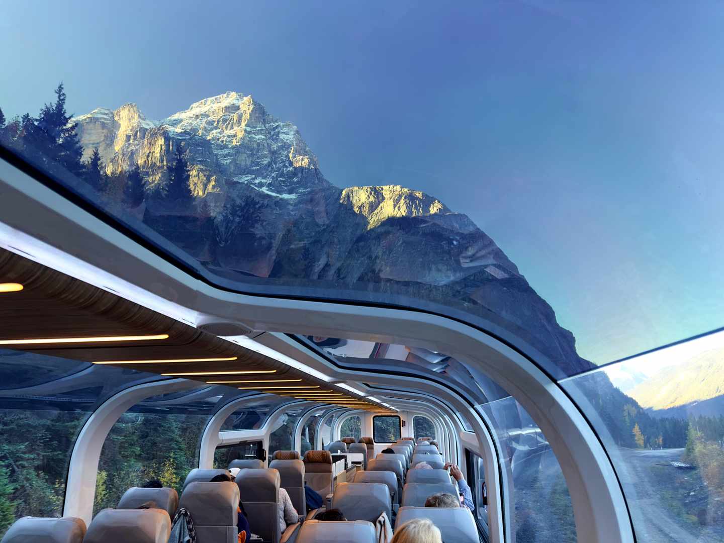 Panoramawagen mit Glasdach vor schneebedeckten Gipfeln der kanadischen Rockies im Banff National Park