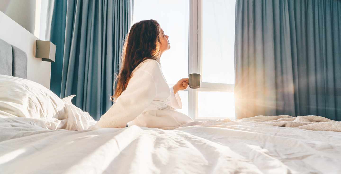sentido-junge-frau-trinkt-morgens-kaffee-auf-hotelbett-g-1340546254.jpg