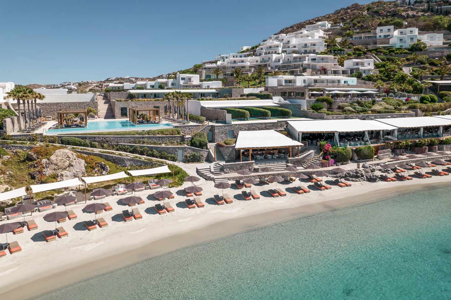 blt1a8274420098af8e-deluxe-aussergewoehnliche-uebernachtungen-santa-marina-mykonos-der1419682.jpg Privatstrand mit Liegen vor terrassenförmig angelegtem Santa Marina, a Luxury Collection Resort auf Mykonos