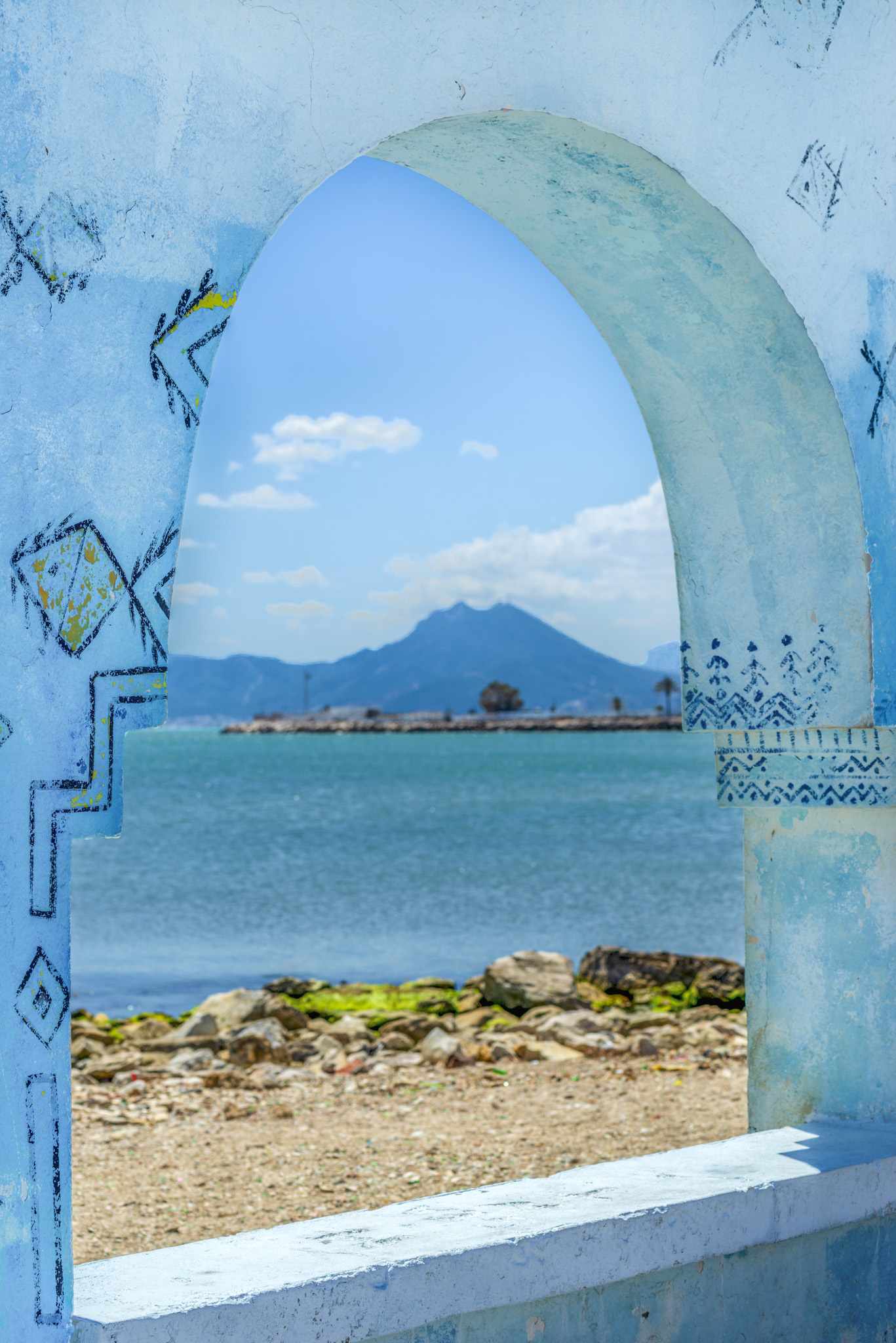GettyImages-1168153081.jpg Blick durch einen blau verzierten Torbogen auf das Mittelmeer und die Küste Tunesiens