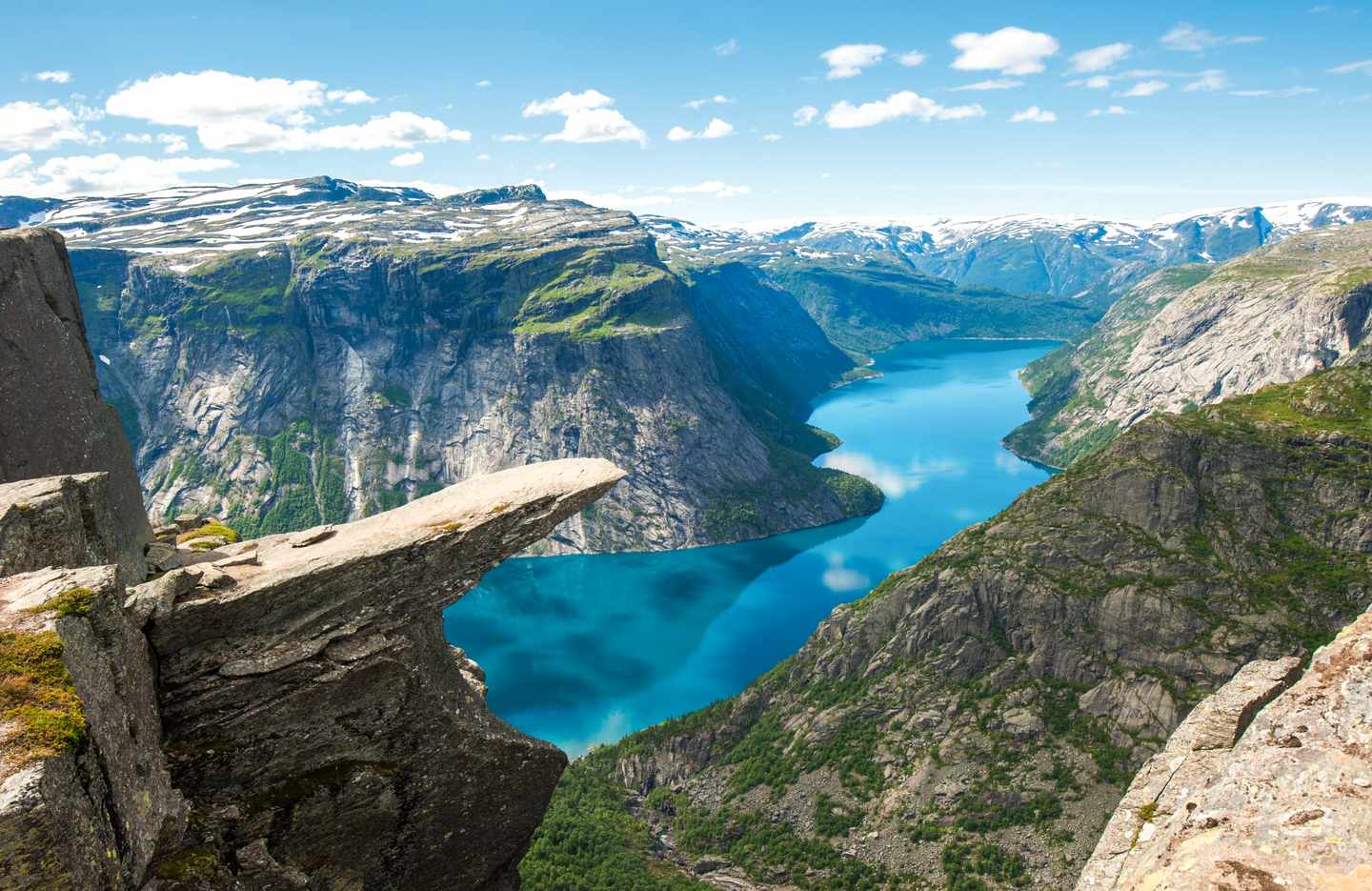 Trolltunga über dem Ringedalsvatnet mit steilen Felswänden und schneebedeckten Bergen in Norwegen