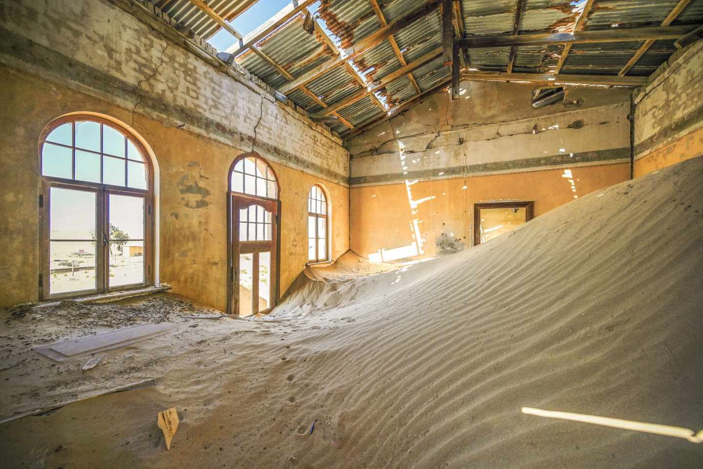 Sanddünen dringen durch Türen und Fenster in ein verlassenes Gebäude der Geisterstadt Kolmanskop in Namibia