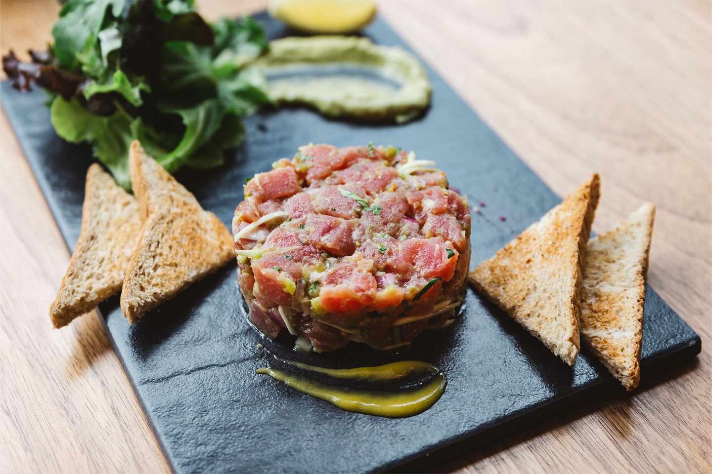 luxus-exklusive-restaurants-in-der-naehe-spicy-bluefin-tartare-mit-sauren-und-wuerzigen-sauce-serviert-mit-toast-und-salat-auf-schwarzem-steinteller-g-1136079735.jpg