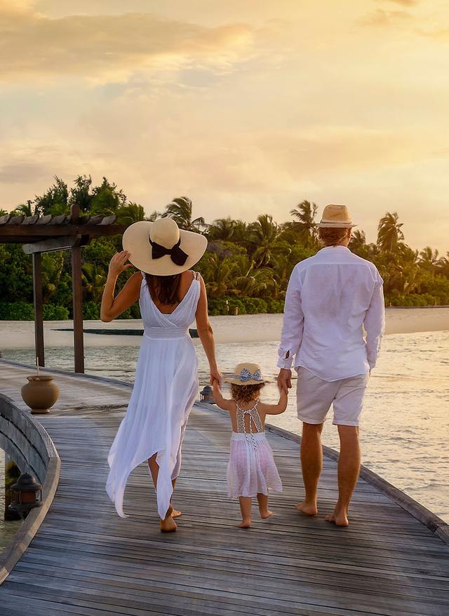 luxus-familienurlaub-eine-familie-geht-haendchenhaltend-ueber-einen-hoelzernen-pier-in-richtung-einer-tropischen-insel-g-1352015722.jpg