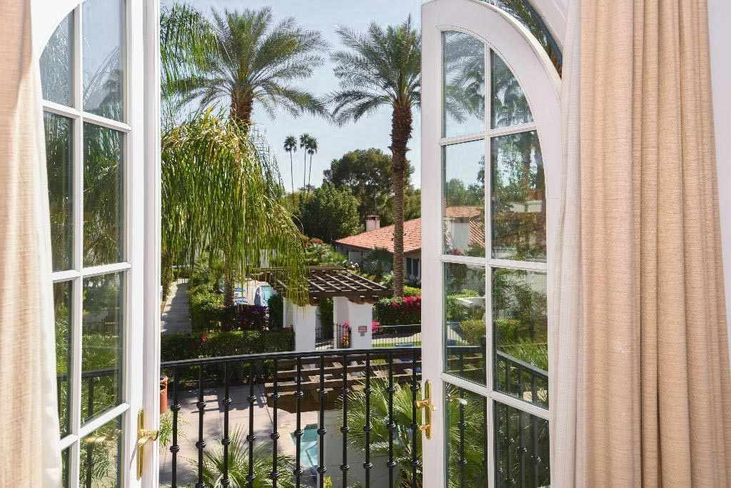 Blick aus einem Zimmerfenster des Coachella-Hotels La Quinta Resort & Club, Curio Collection by Hilton auf die Gartenanlage mit Pool und Palmen