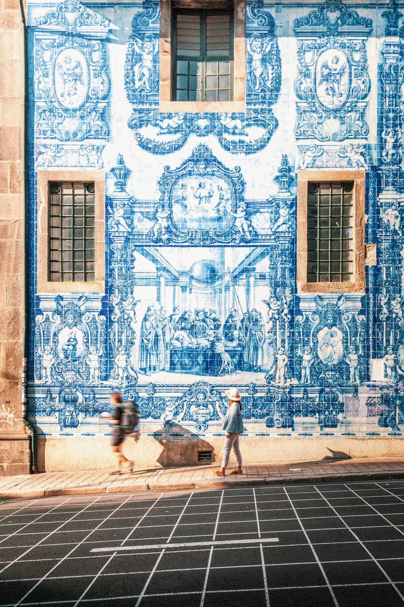 Fußgänger vor den blau-weißen Azulejos der Capela das Almas in Porto, Portugal