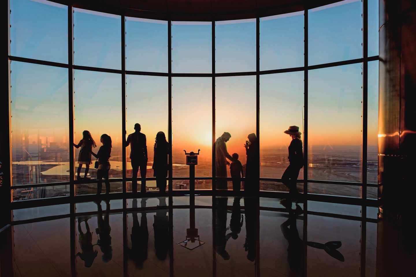blt808941b71b5eb74d-vae-dubai-burjkhalifa-d-1480427.jpg Mehrere Besucher auf einer Aussichtsplattform des Burj Khalifa, im Hintergrund ein Sonnenuntergang