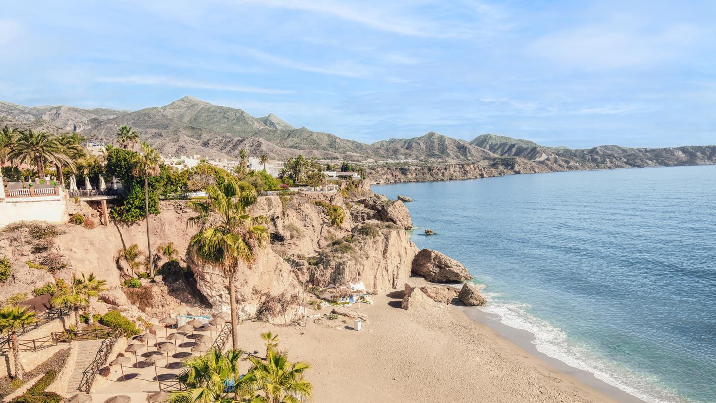 Felsige Bucht mit dahinterliegender Stadt und blauem Meer