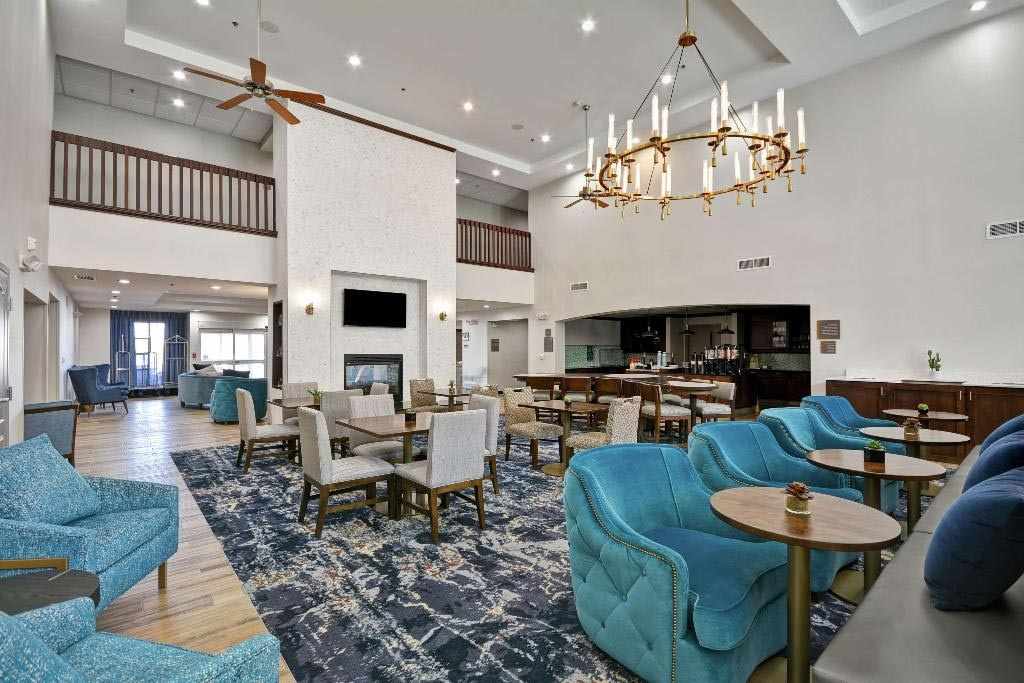 Salon mit blauen Samtsesseln und grauen Polsterstühlen an Tischen im Coachella-Hotel Homewood Suites by Hilton Palm Desert