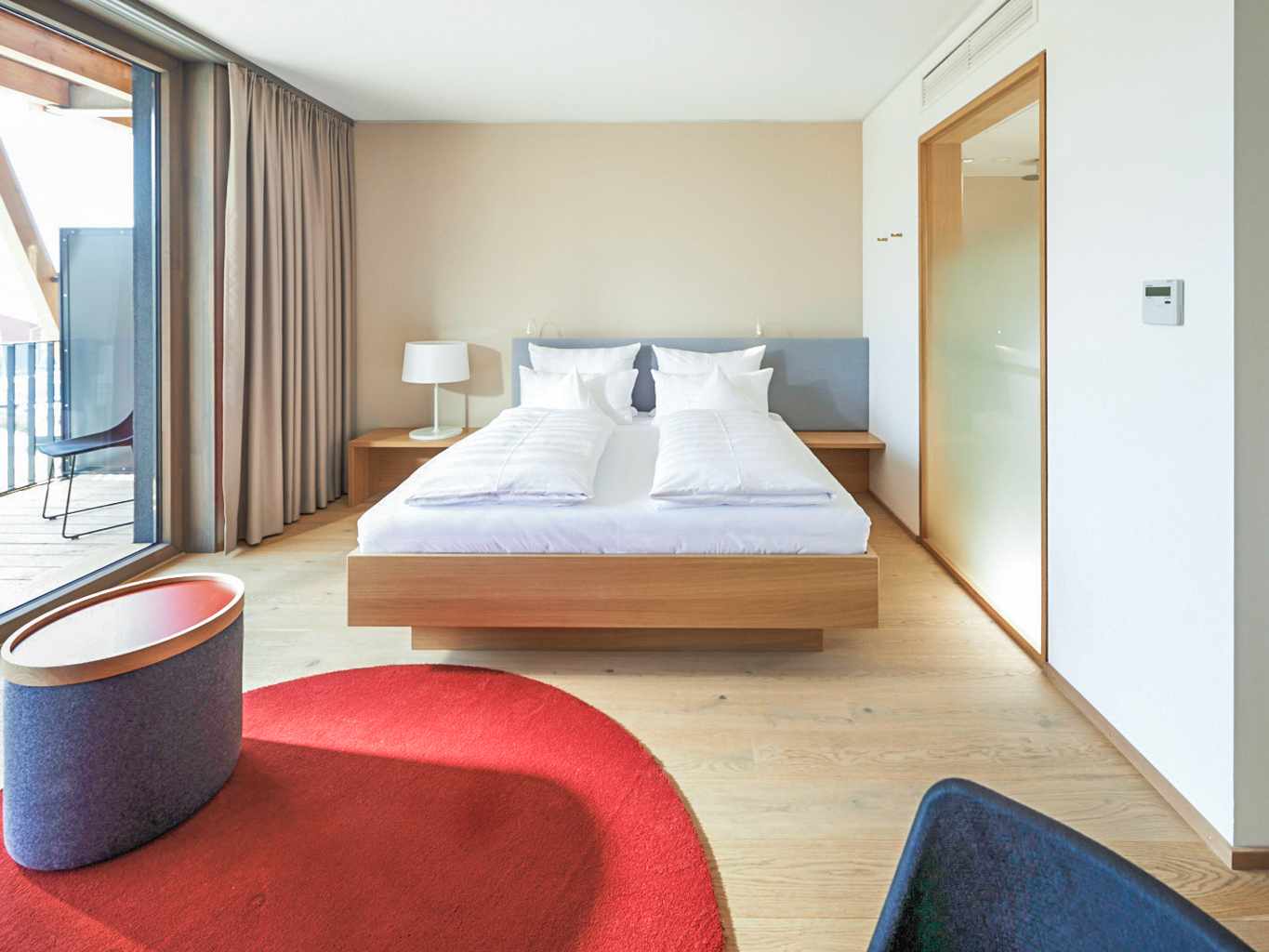 blt32b2de9d0e500c05-deutschland-radolfzell-bodensee-bora-hotsparesort-doppelzimmer-balkon-wellnesshotel-DER1357461.jpg Modernes Doppelzimmer im bora HotSpaResort Radolfzell mit Balkon, Holzboden und klarer Raumgestaltung