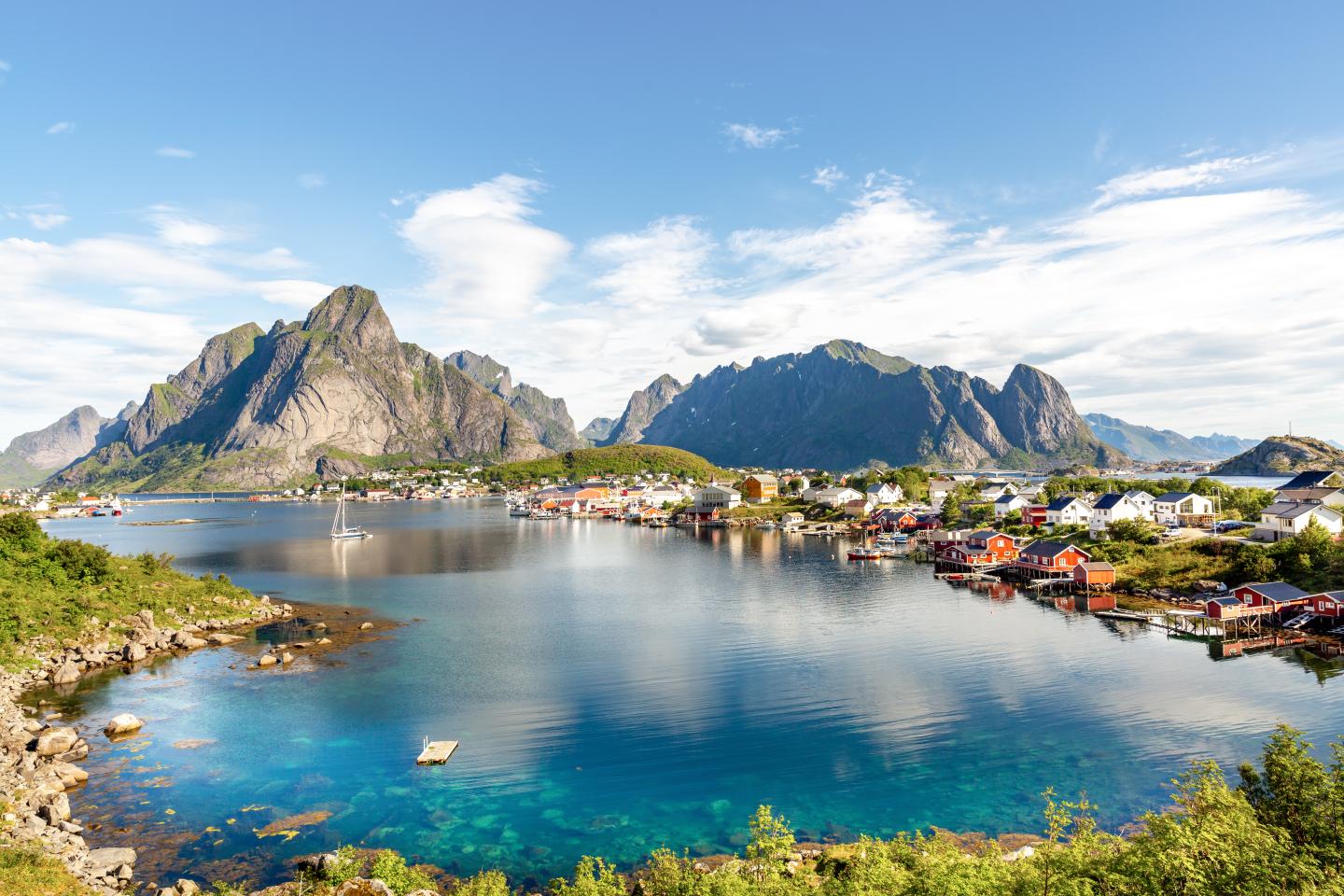 GettyImages-1275865850.jpg Rorbuer-Holzhütten am Fjord bei Reine mit Bergkulisse auf den Lofoten in Nordnorwegen