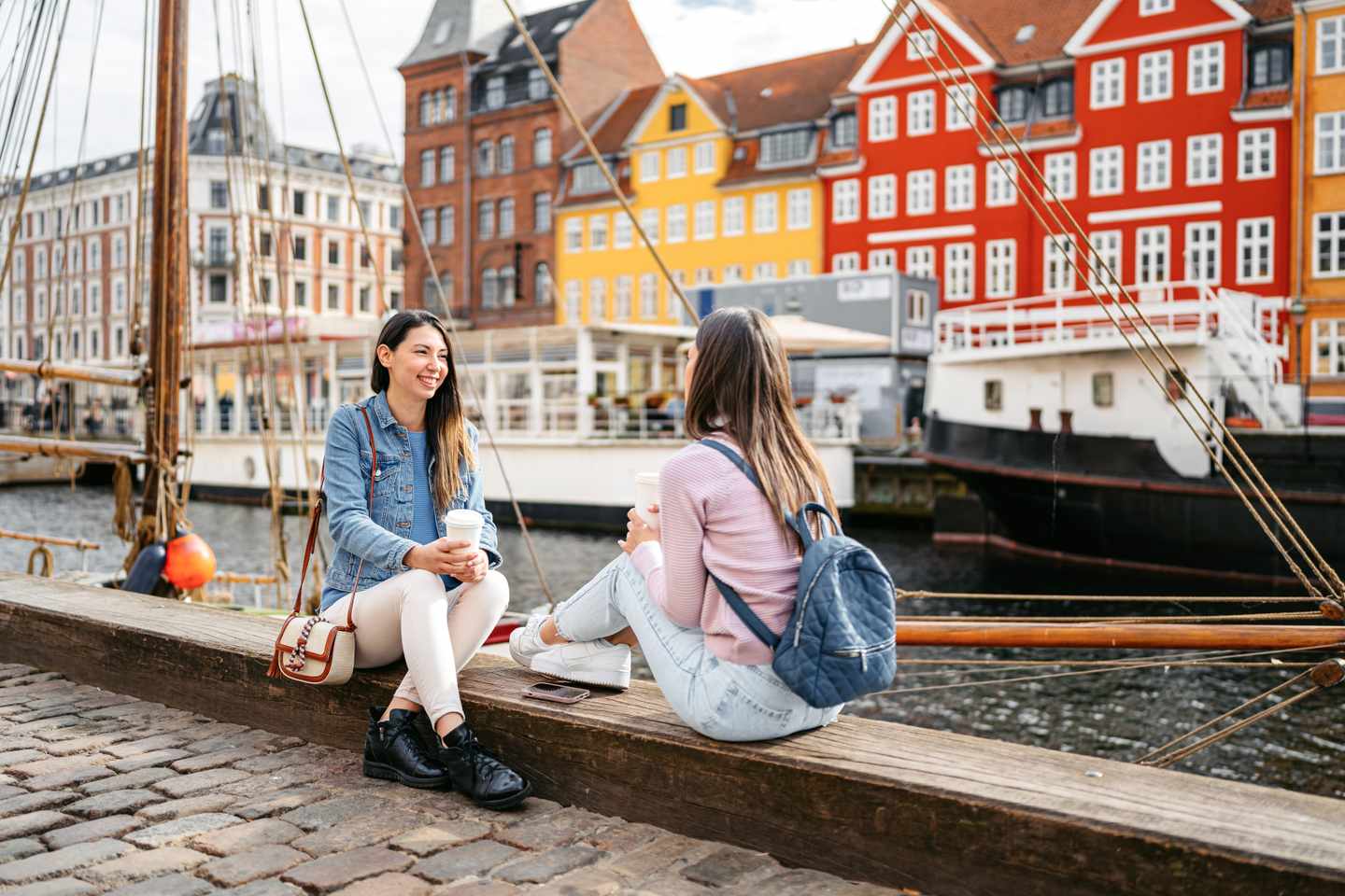 nordeuropa-daenemark-zwei-junge-frauen-sitzen-am-nyhavn-kanal-in-kopenhagen-g-1792722300.jpg