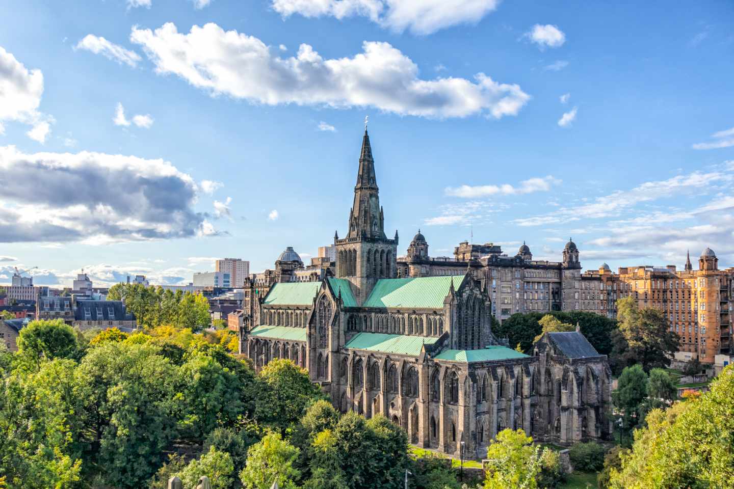 Glasgow Cathedral mit hohem Turm und historischer Steinfassade über einer grünen Parkanlage in Glasgow