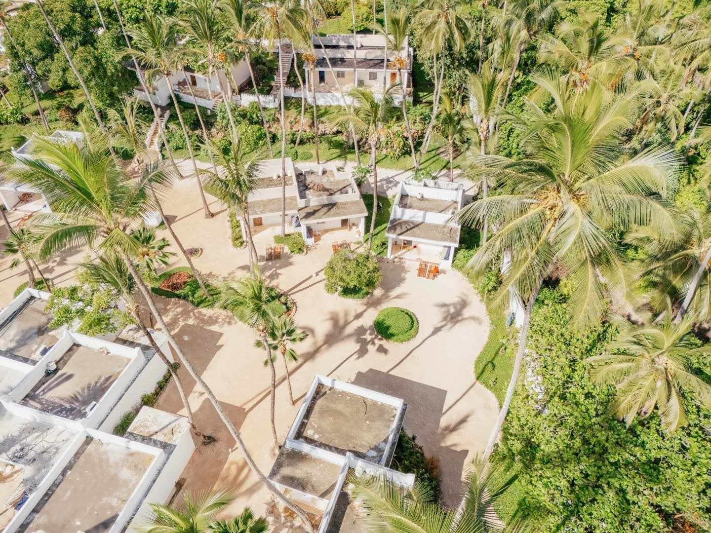 Luftaufnahme der Bungalows im ananea Diamonds Mapenzi in Kiwengwa, Sansibar – umgeben von hohen Palmen, tropischem Grün und sandigen Wegen