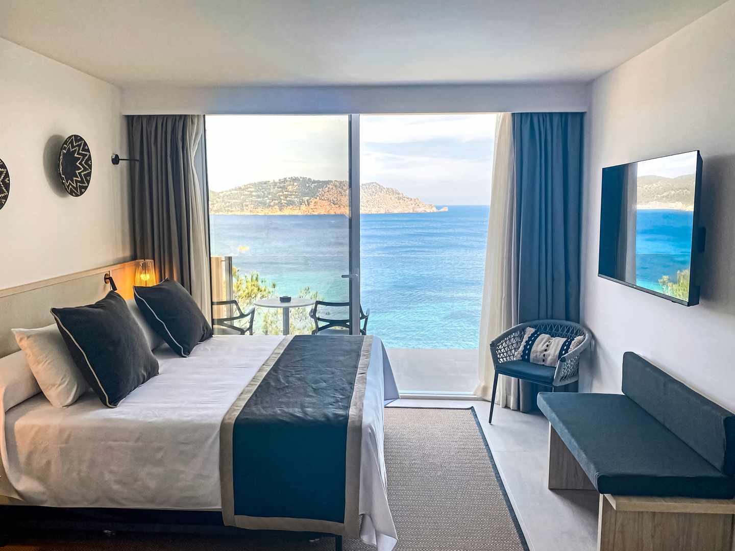blt9a8793a4ac4f2f2d-spanien-ibiza-sentido-cala-verde-zimmer-panoramablick-meer-DER1492843.jpg Zimmer im Sentido Cala Verde auf Ibiza mit Doppelbett, Sitzmöbeln, Wand-TV und Panoramafenster mit Blick auf das Mittelmeer
