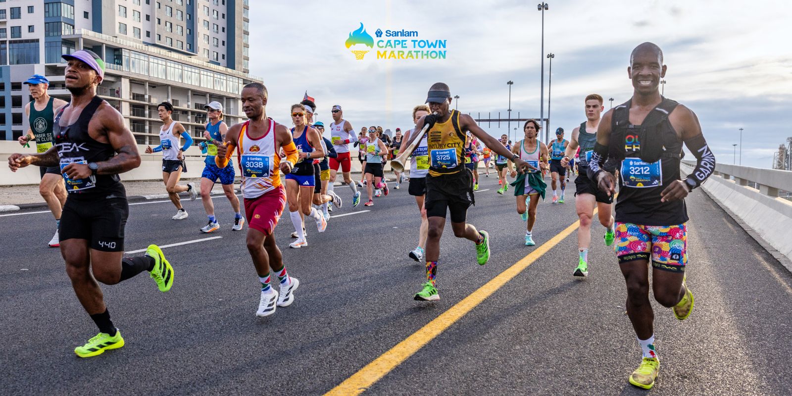Läufer in bunter Trainingskleidung joggen über eine Brücke in Kapstadt beim Cape Town Marathon