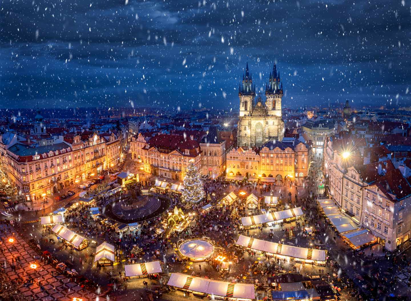 Verschneiter Weihnachtsmarkt auf dem Altstädter Ring in Prag mit beleuchteten Buden und Teynkirche