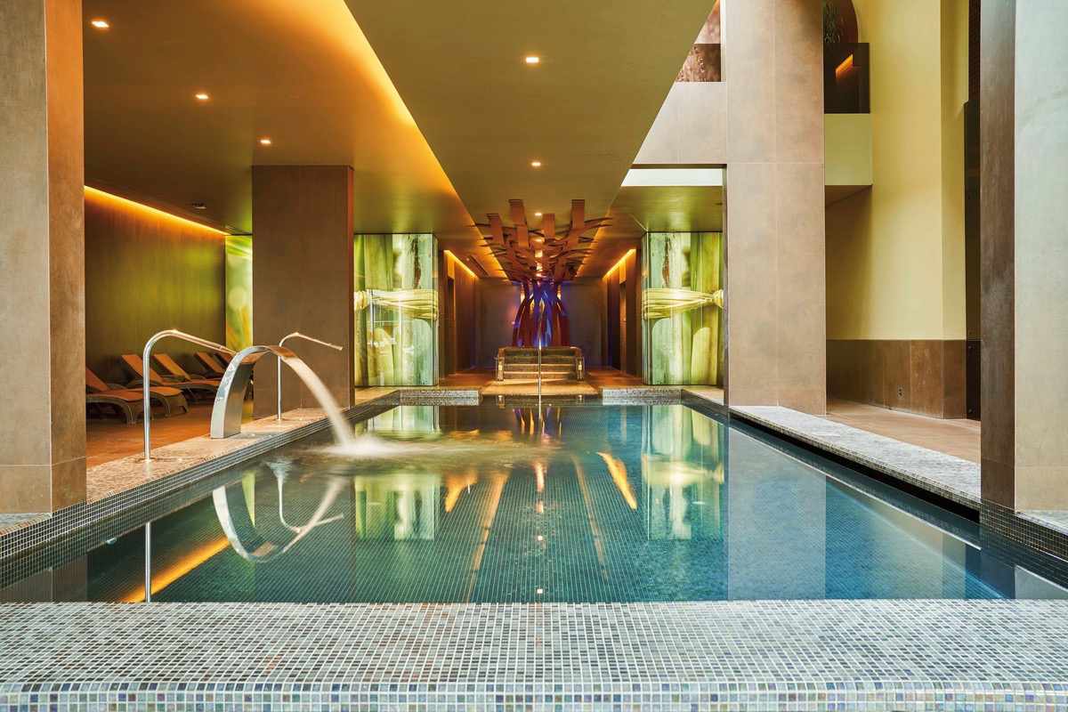 Indoorpool des Saccharum Resorts umgeben von kleinen Fliesen und warmer Beleuchtung