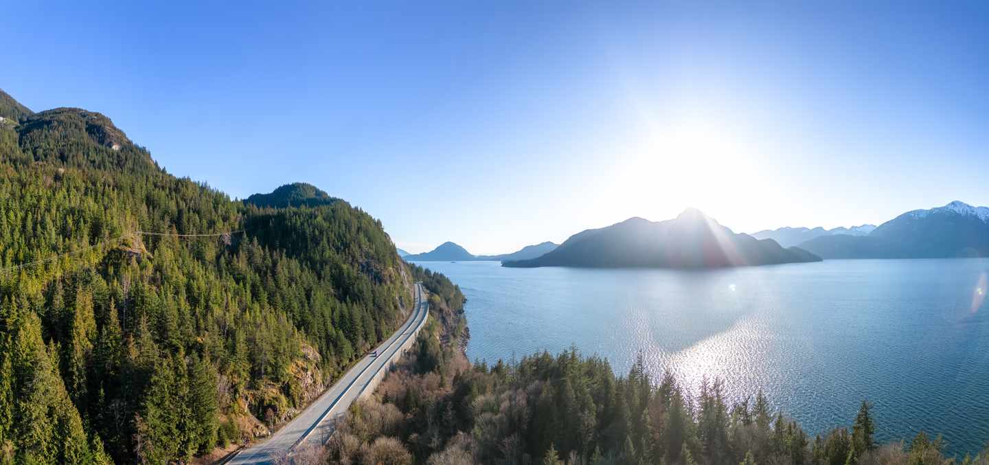 Sea to Sky Highway entlang des Howe Sound mit bewaldeten Bergen und tiefblauem Wasser in British Columbia