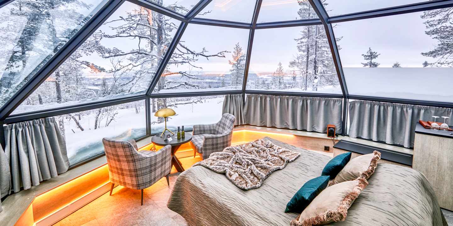 blta5755c2eaefeaf70-polarlichter-hotels-Levin_Iglut-DER1366309.jpg Bett in einem Glas-Iglu, Schneelandschaft hinter den großen Fenstern