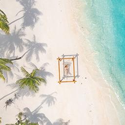 Eine Frau in einer Hängematte am Strand auf den Malediven