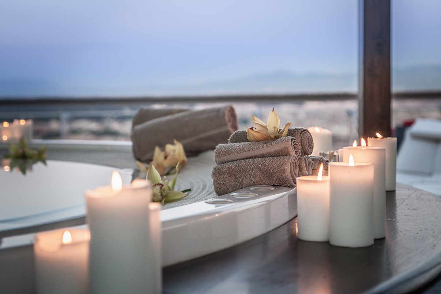 Whirlpool mit Kerzen Handtüchern und Blüten vor einem Fenster