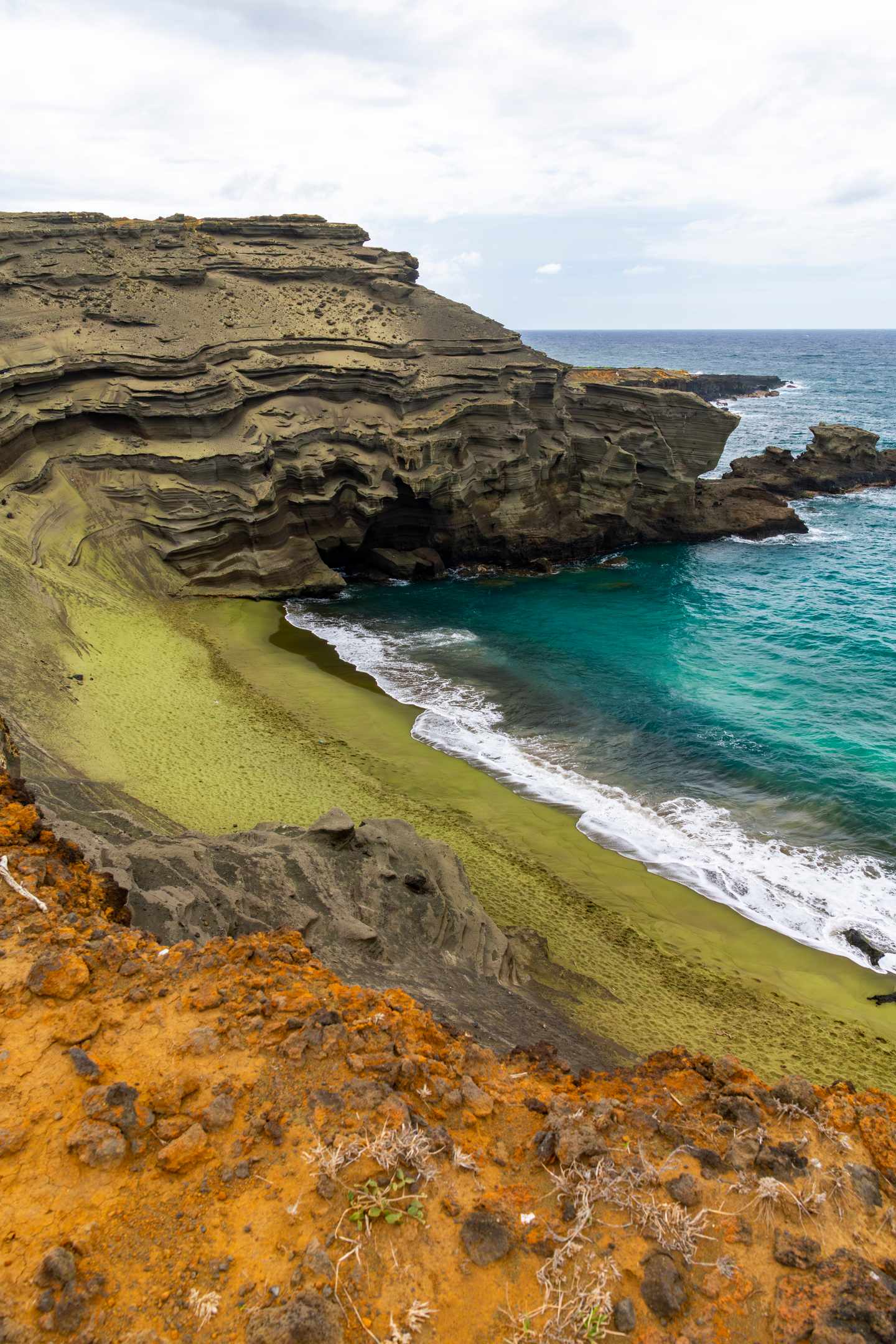 GettyImages-2234799858.jpg Der grüne Sandstrand von Papakōlea auf der Big Island von Hawaii mit seltenem grünem Olivinsand und schroffen Vulkanfelsen entlang der Küste.