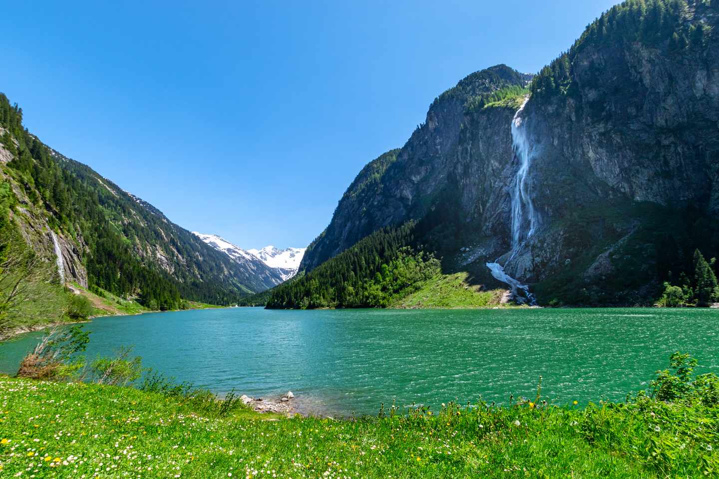 Wellnesshotel im Zillertal: Berglandschaft mit klarem türkisfarbenem See und Wasserfall in den Alpen
