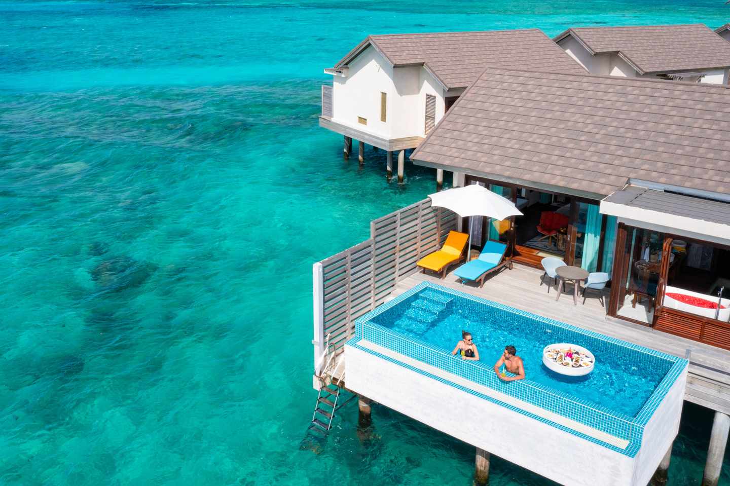 blt78f3d672aad1b2bd-ATMOSPHERE_KANIFUSHI_MALDIVES_-_SUNSET_WATER_VILLA_WITH_POOL_-_AERIAL_-_FLOATING_BREAKFAST_-_LIFESTYLE_01_-_09_2023.jpg Atmosphere Kanifushi Maldives - Sunset Wasser Villa - Blick von oben - Paar badet im Pool und genießt den Urlaub