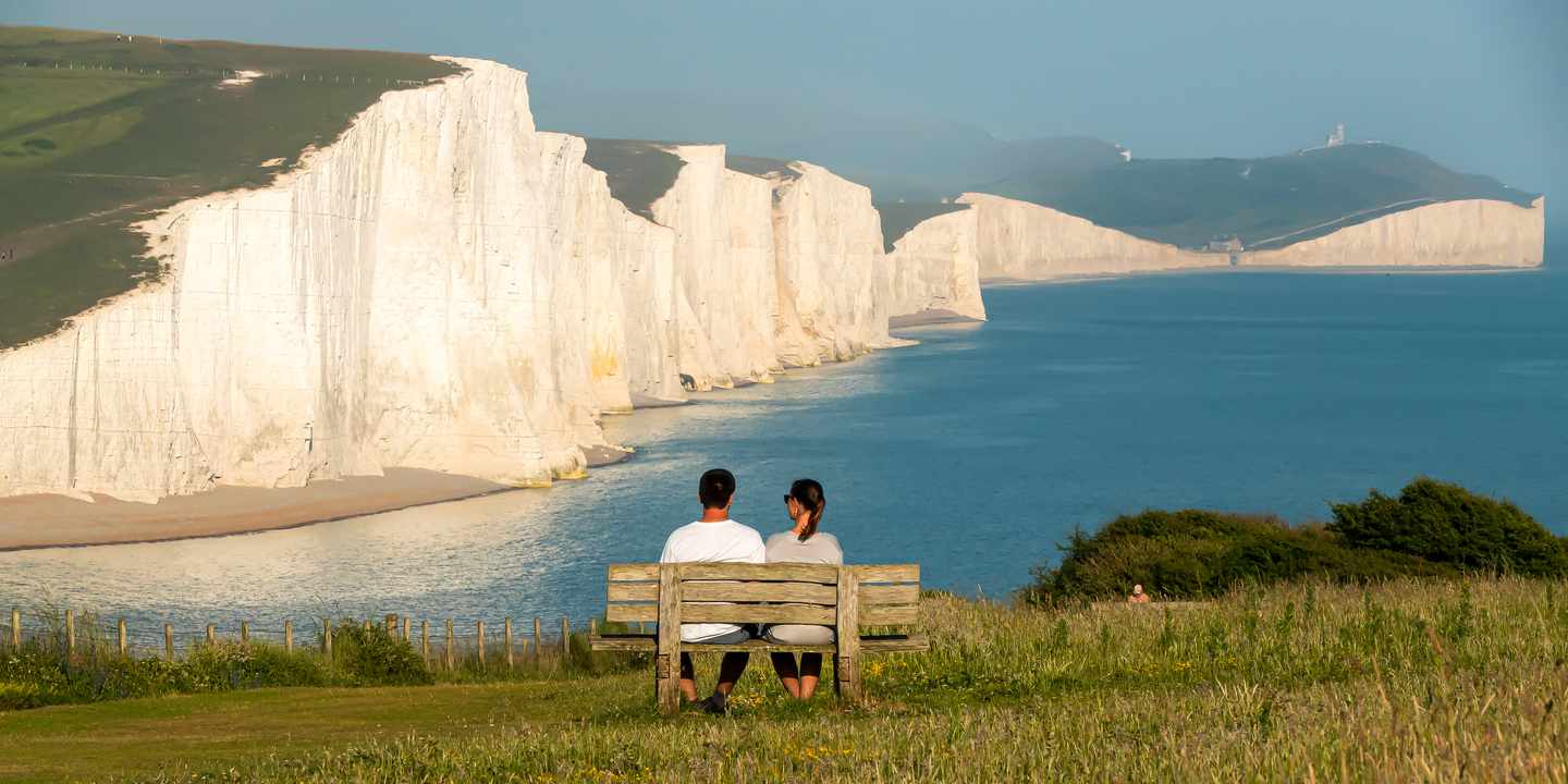 grossbritannien-südengland-east-sussex-south-downs-nationalpark-kreidefelsen-seven-sisters-paar-bank-g-2013309424.jpg