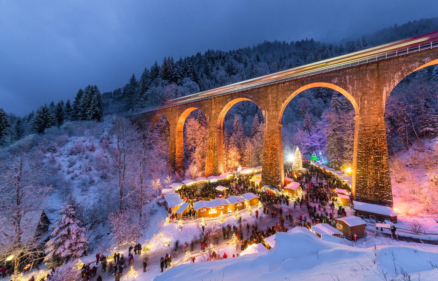 GettyImages-1481713960-2.jpg Weihnachtsmarkt in der verschneiten Ravennaschlucht unter dem beleuchteten Viadukt der Höllentalbahn