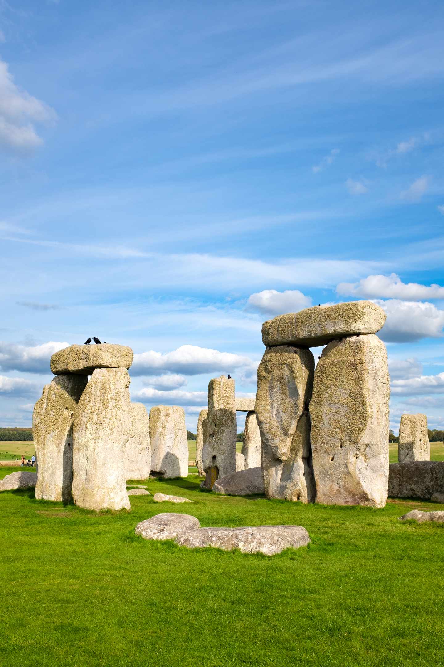 Megalithen von Stonehenge auf einer grünen Wiese unter blauem Himmel mit lockeren Wolkenformationen