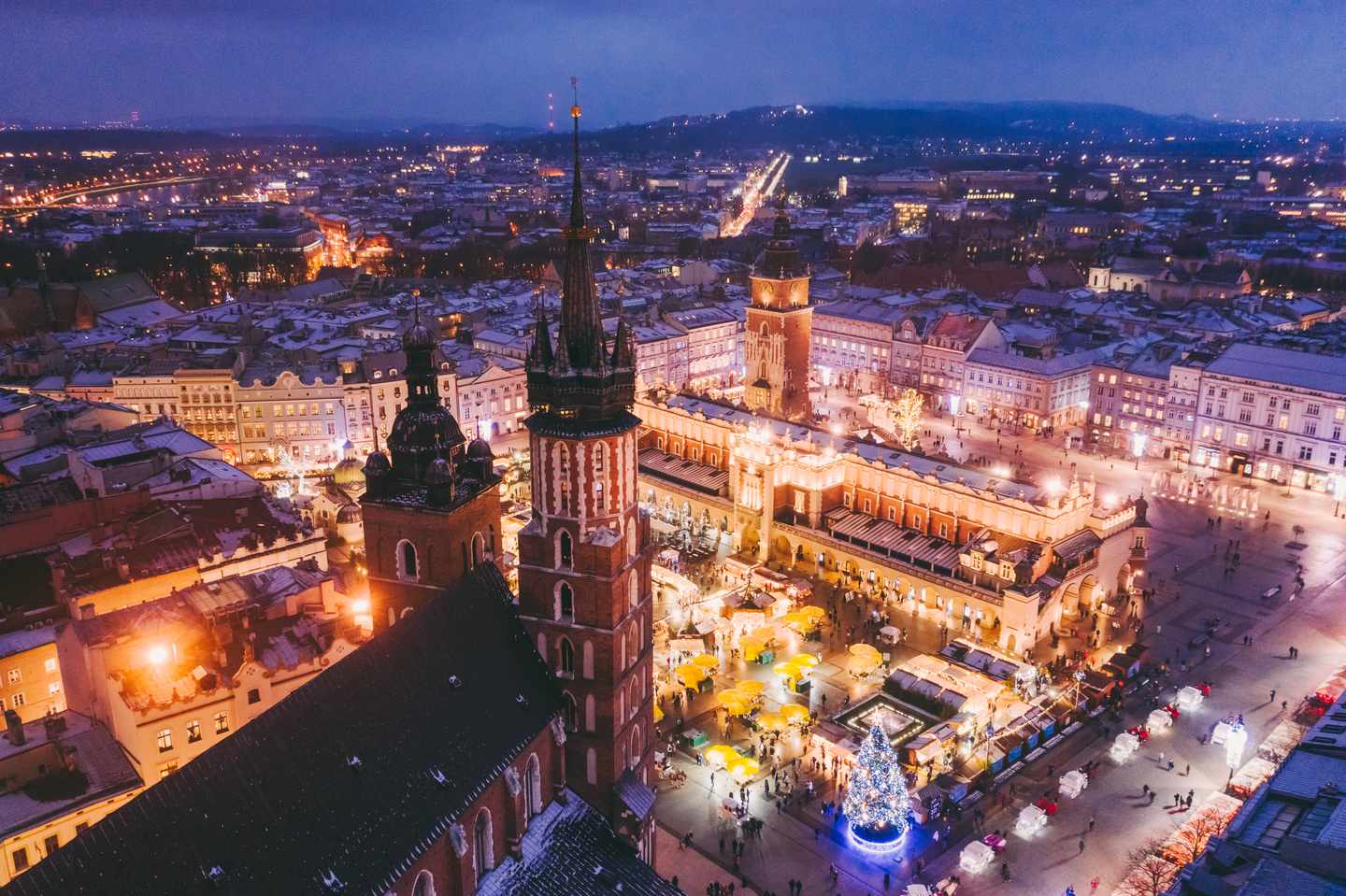 Weihnachtsmarkt auf dem Krakauer Hauptmarkt bei Nacht mit beleuchtetem Weihnachtsbaum und Marienkirche