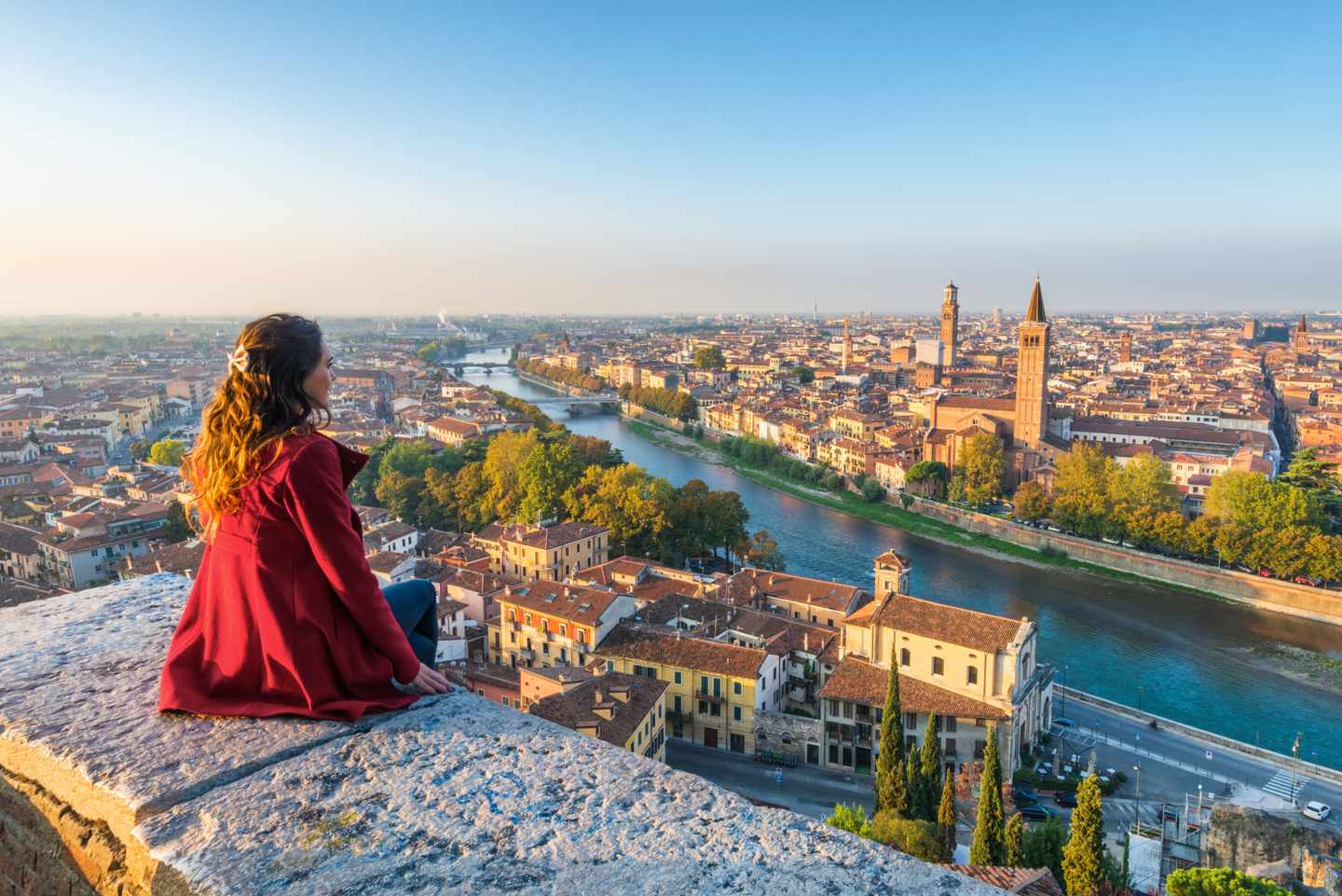 Alleinreisende Frau blickt vom Castel San Pietro über die Dächer Veronas und den Fluss Etsch