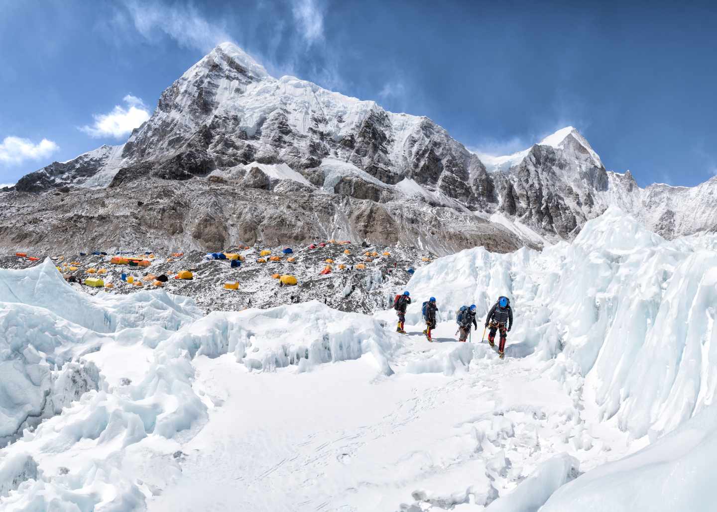 Bergsteiger zwischen Eisformationen am Everest Base Camp vor schneebedeckten Gipfeln im Himalaya in Nepal