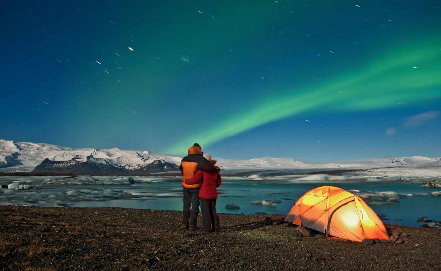 Romantische Aussichten: Ein Paar betrachtet das spektakuläre Nordlicht über einem See auf Island.