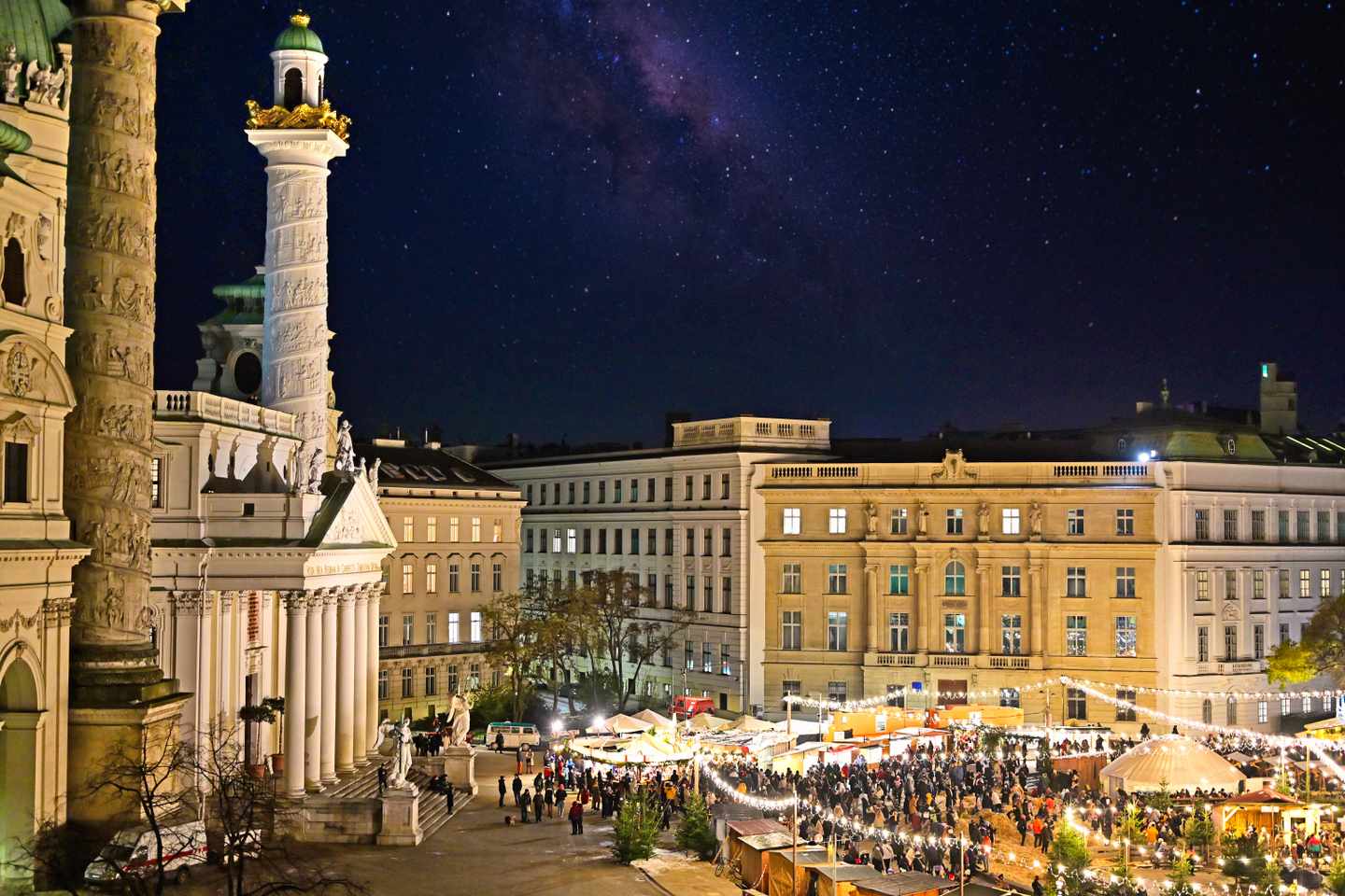 Weihnachtsmarkt am Wiener Karlsplatz bei Nacht mit beleuchteten Ständen vor der Karlskirche