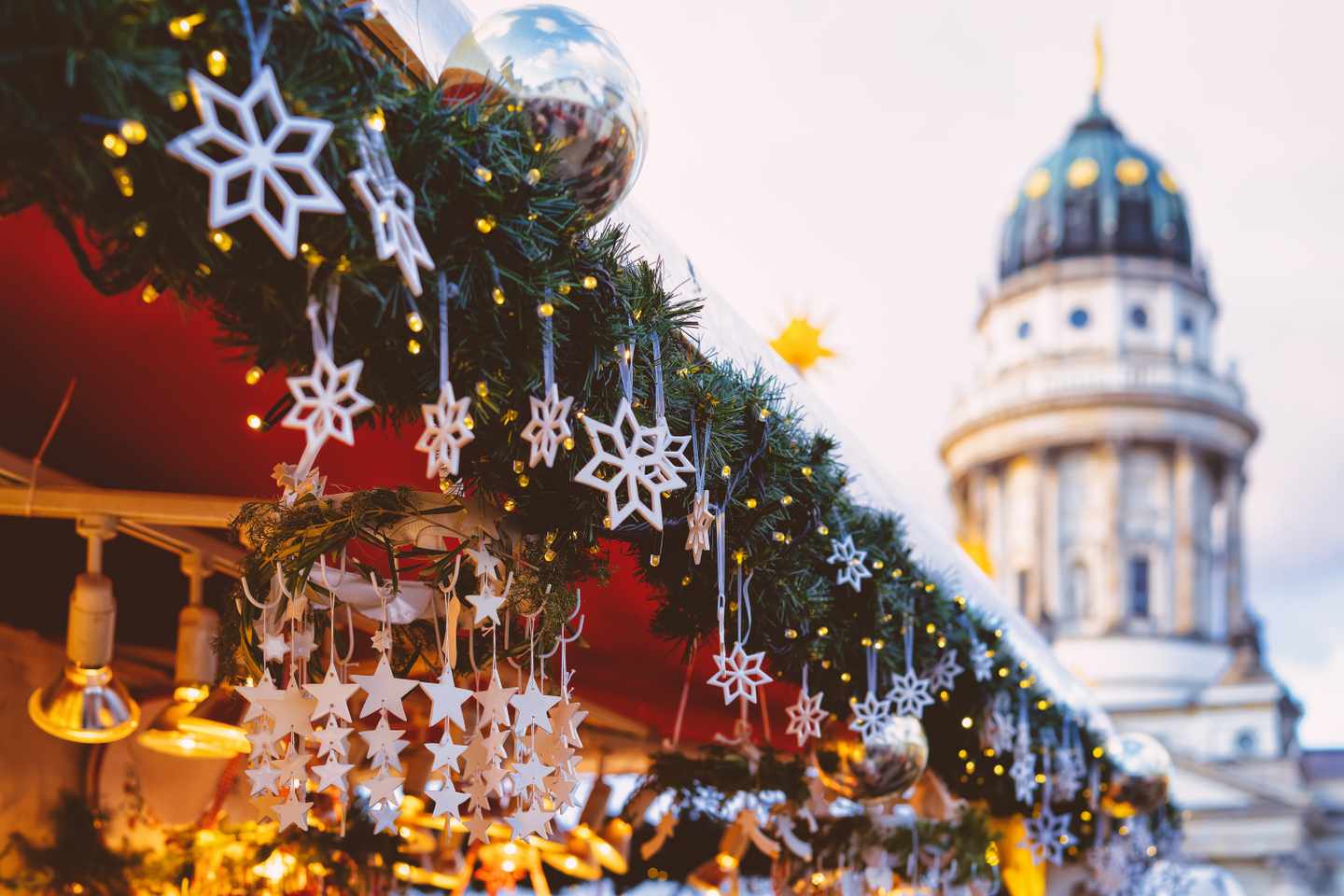 Geschmückter Weihnachtsstand am Berliner Gendarmenmarkt mit Sternen Lichterketten und Deutschem Dom